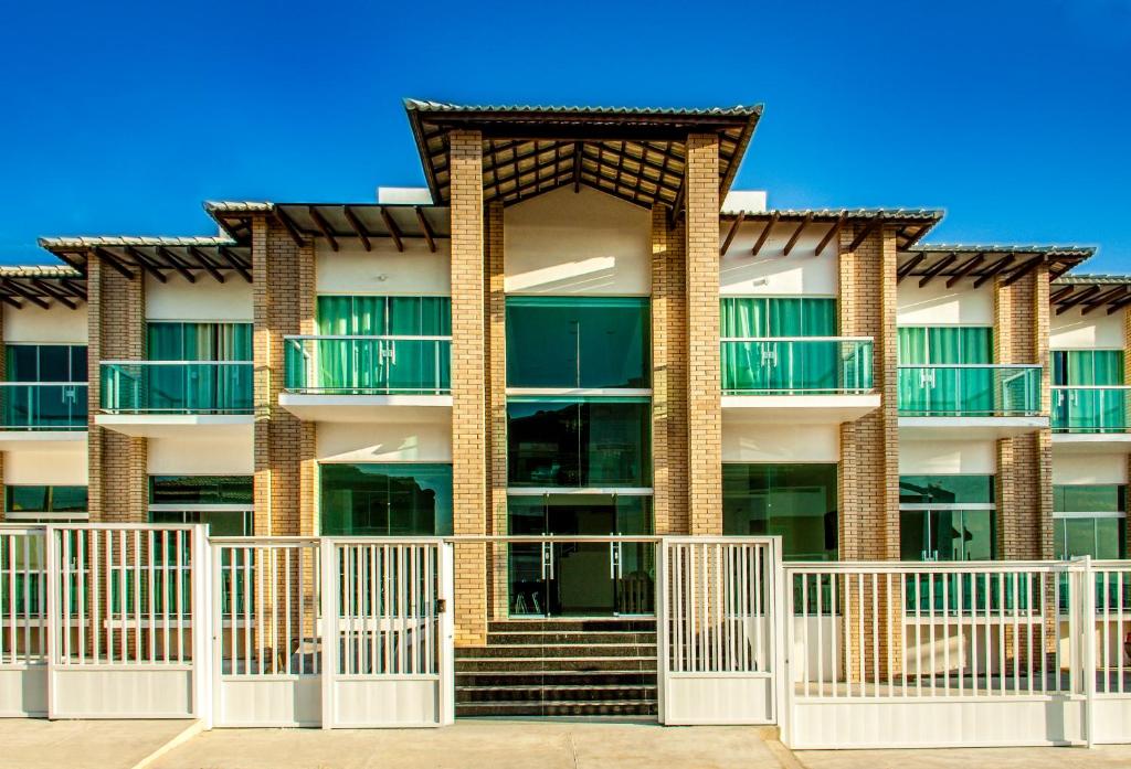 um edifício de apartamentos com uma cerca branca em frente em Pousada Villa Mares em São Pedro da Aldeia