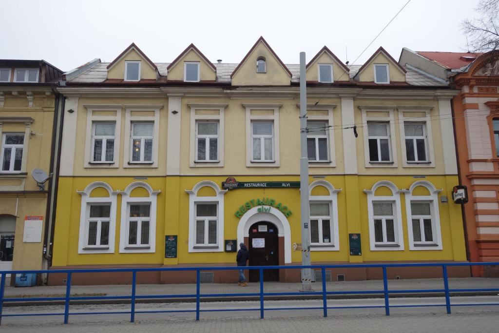 um edifício amarelo com uma pessoa à frente dele em Restaurace ALVI em Ostrava