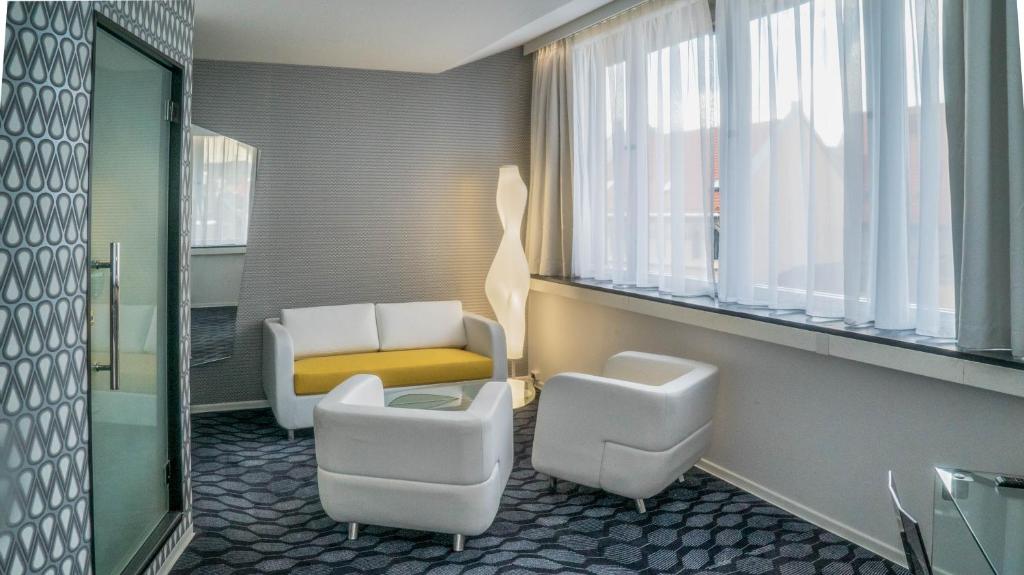 um quarto com duas cadeiras, um sofá e janelas em Magic Hotel Korskirken em Bergen