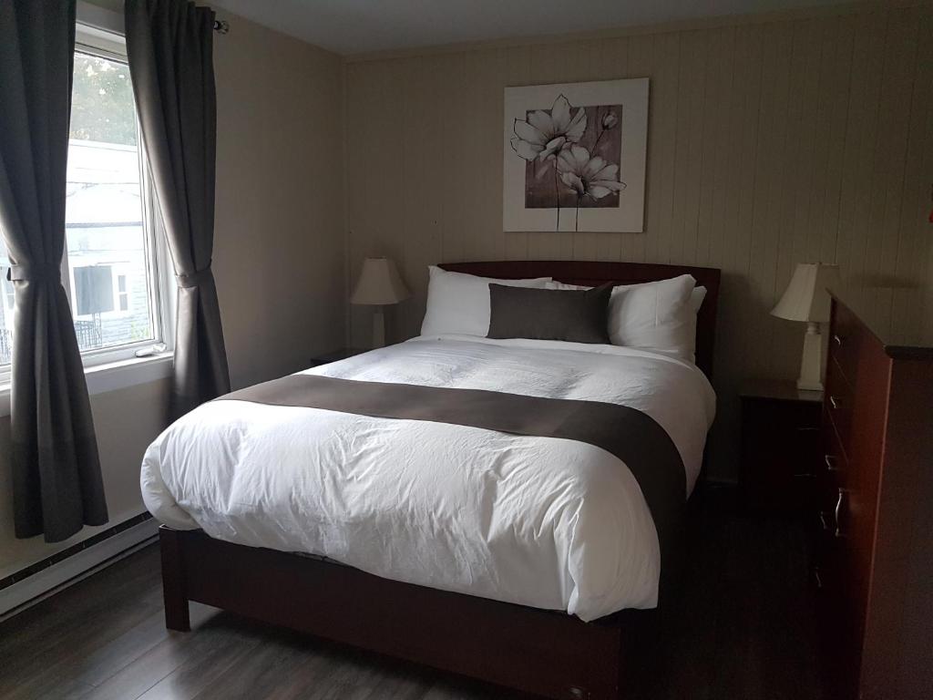 a bedroom with a large bed with white sheets at 1-Bedroom Apartment Sweet #3 by Amazing Property Rentals in Gatineau