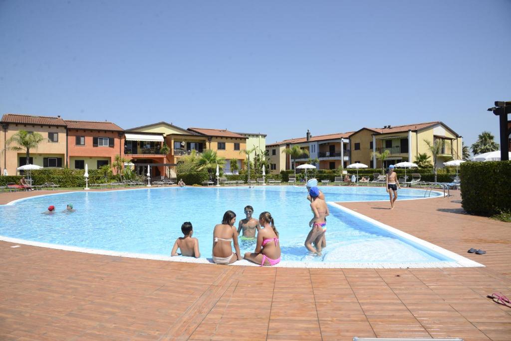 ポリコーロにあるI Giardini Eliseiのリゾートのプールに宿泊する人々のグループ