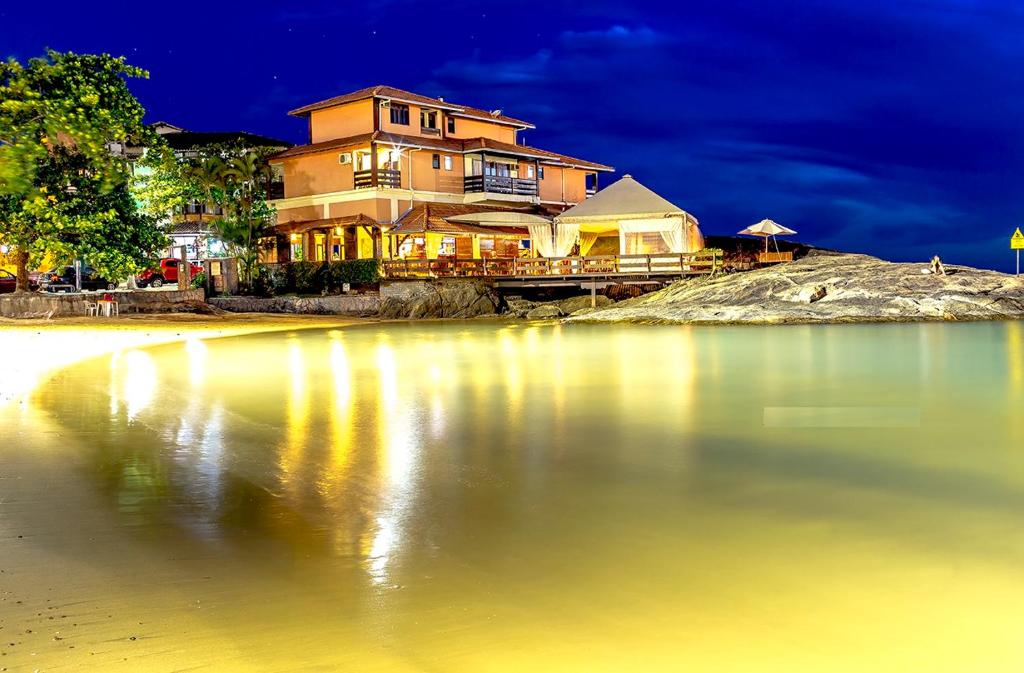 a house on the shore of a lake at night at Pousada Recanto da Pedra in Iriri