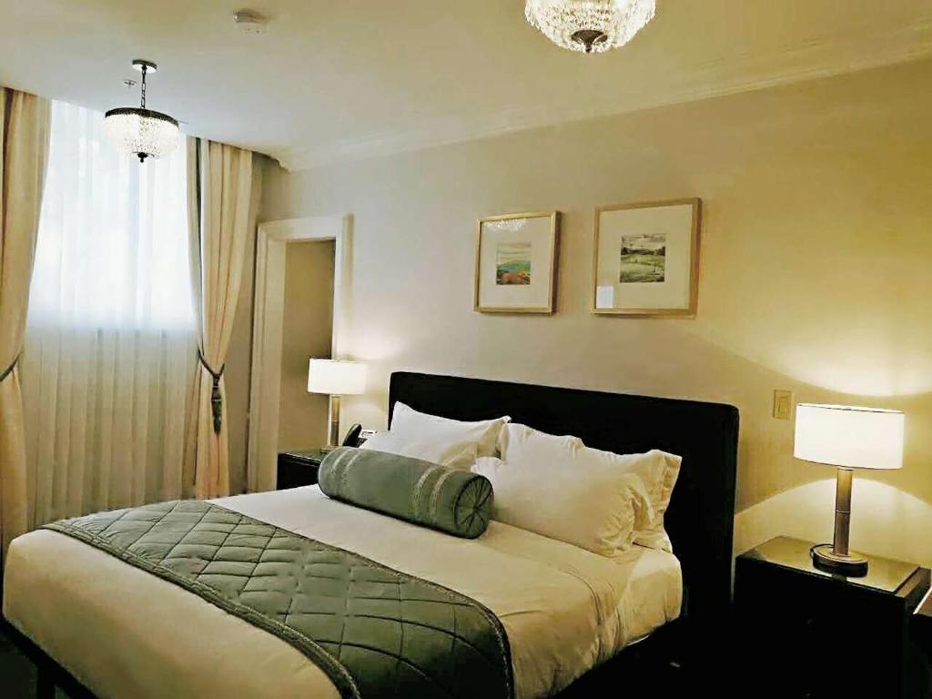 a bedroom with a bed and two lamps and a window at Sydney Boutique Inn & Suites in Charlottetown