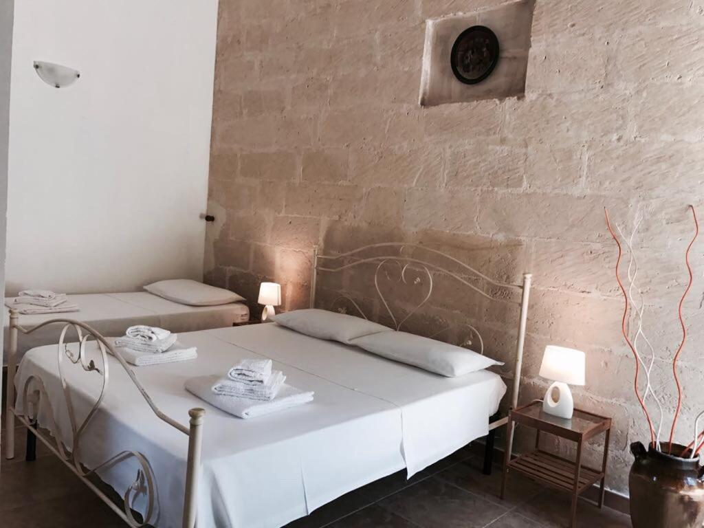 サン・チェザーリオ・ディ・レッチェにあるTenuta "Li Santi"のレンガの壁、ベッド2台が備わるベッドルーム1室が備わります。