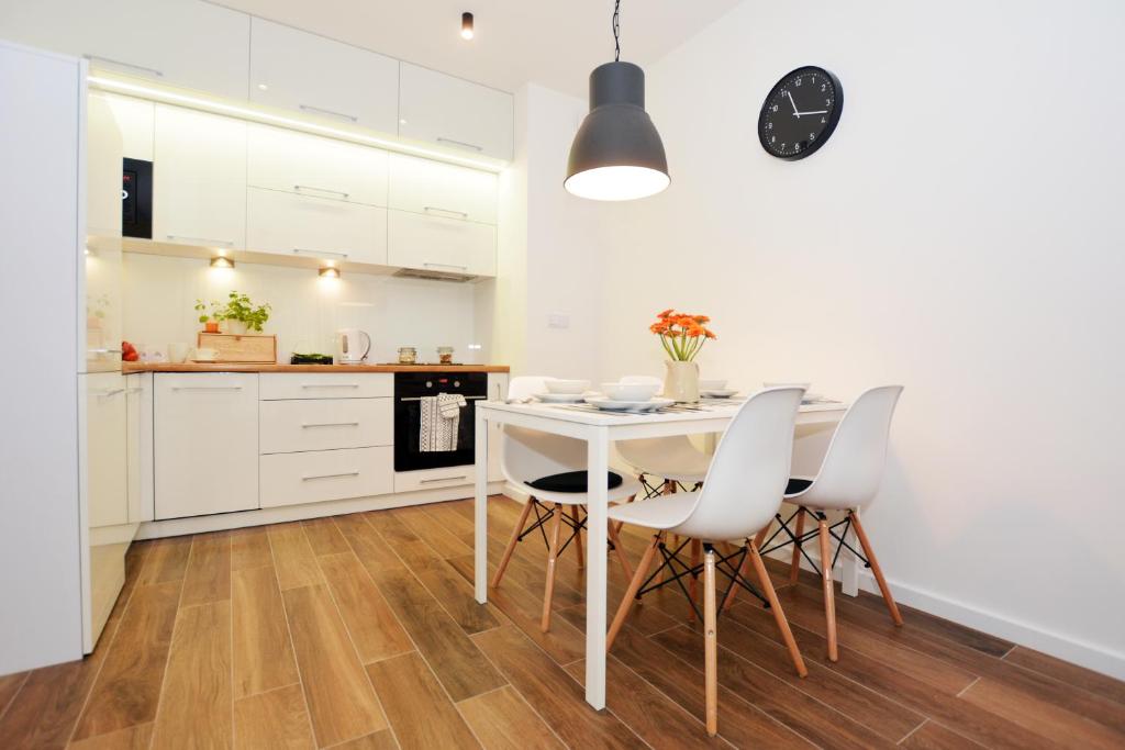 a kitchen with white cabinets and a white table and chairs at Apartament 27 Dwie Sosny in Ustronie Morskie