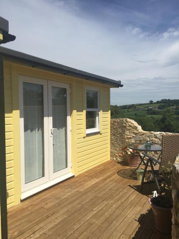 a yellow house with a deck with a table at The Retreat in Charmouth