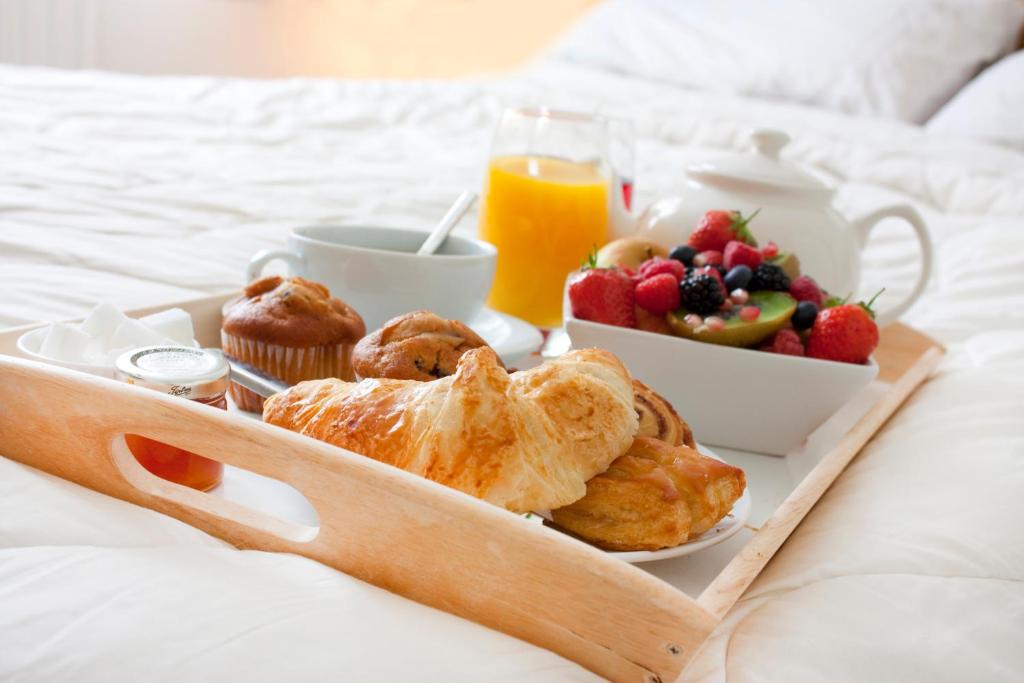 a breakfast tray with pastries and fruit on a bed at Bed & Breakfast Giethoorn in Giethoorn