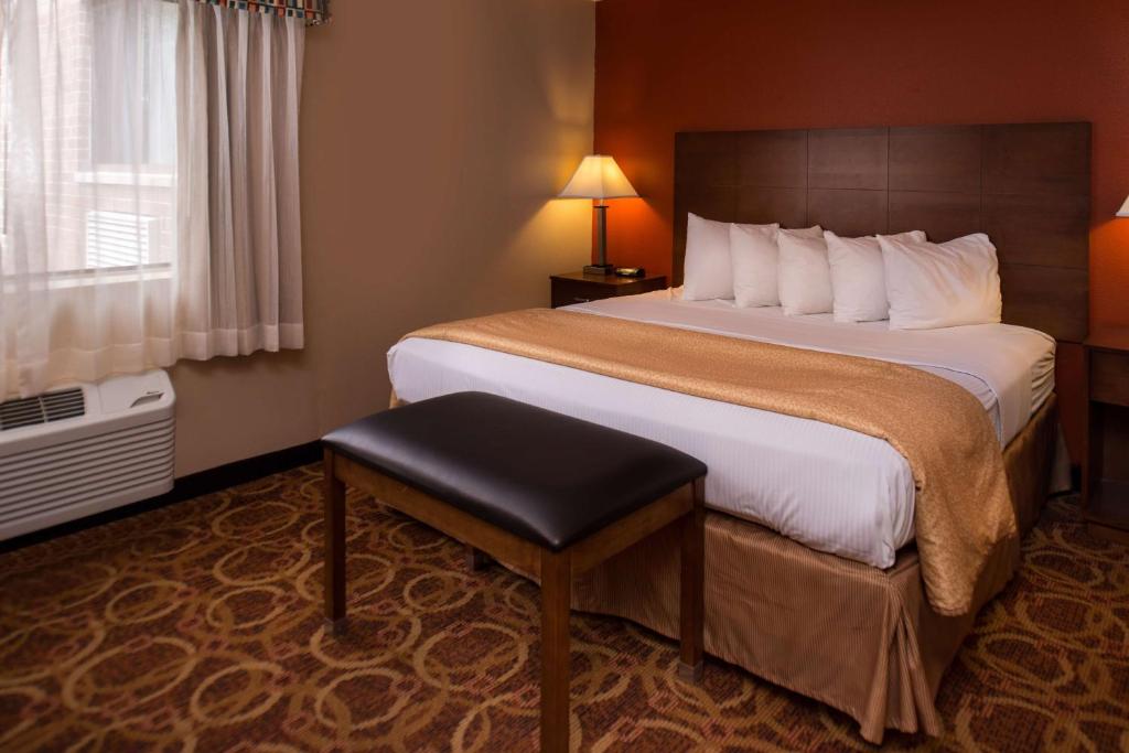 a hotel room with a large bed and a stool at Best Western Ambassador Inn & Suites in Wisconsin Dells