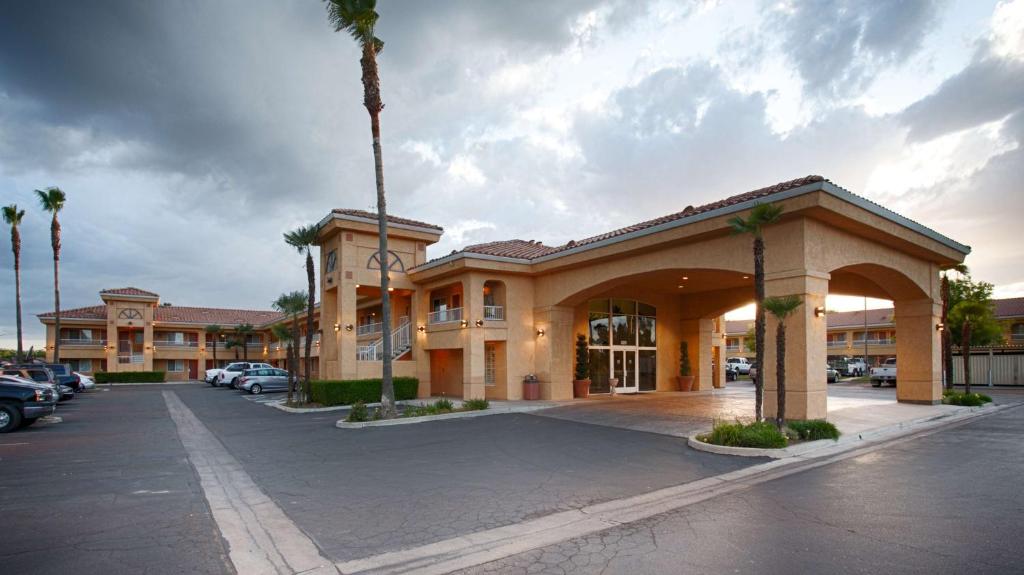 a building with a palm tree in a parking lot at Best Western Inn & Suites Lemoore in Lemoore