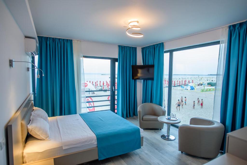 a hotel room with a bed and a view of the beach at Belleview Suites in Mamaia