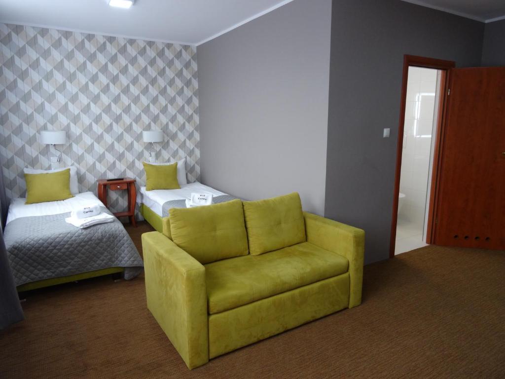 a living room with a yellow chair and a bed at Carina Hotel in Tczew