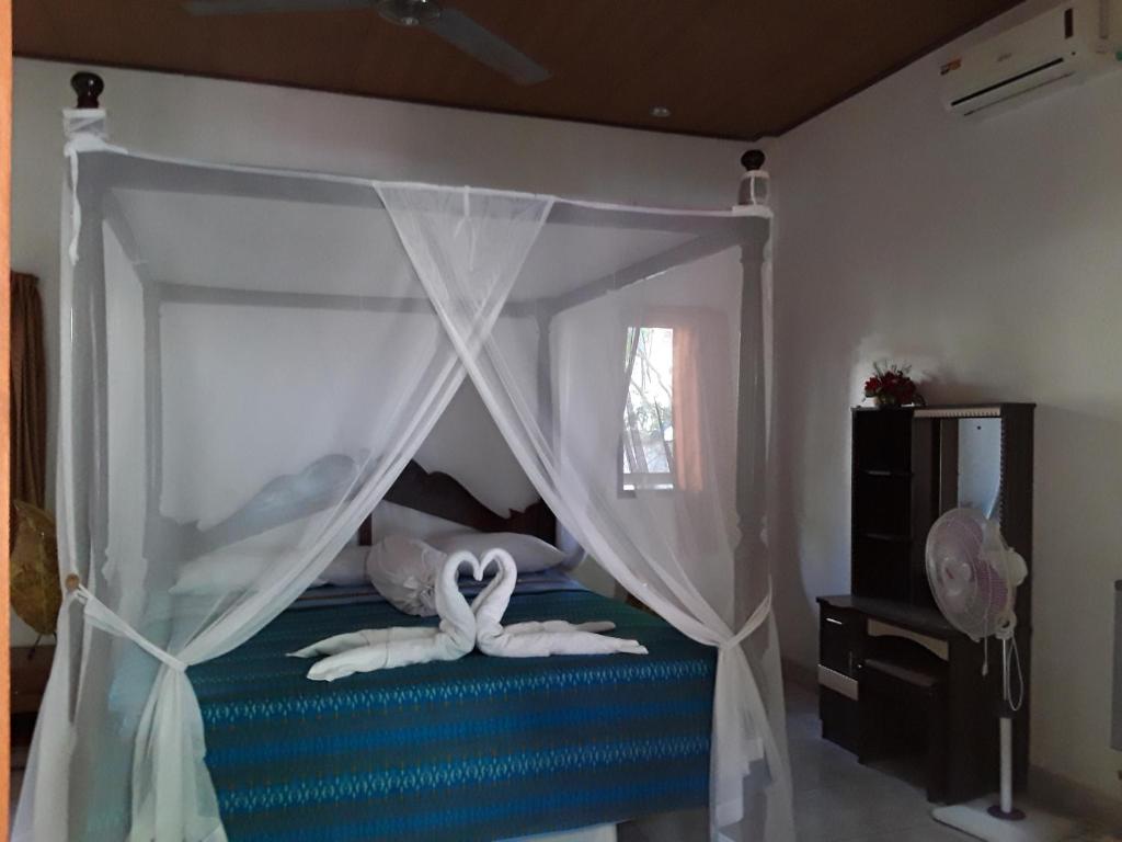 a bedroom with a canopy bed with swans on it at Blue Star Bungalows & Cafe in Amed