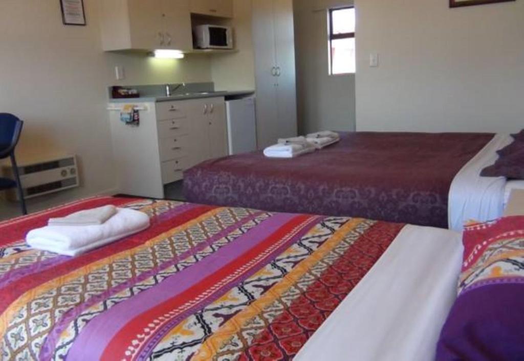 a hotel room with two beds and a kitchen at AAA Northlands Motel in Christchurch