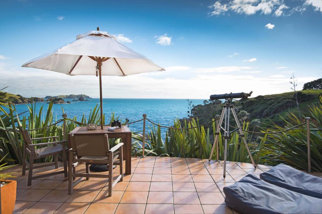 a table with an umbrella and a camera at Crab Cove in Mahinepua