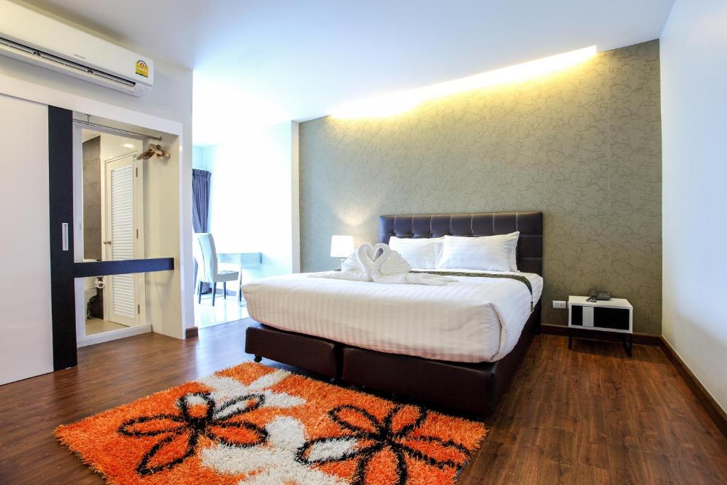 1 dormitorio con 1 cama con alfombra naranja en Romyen Garden Place en Nakhon Ratchasima