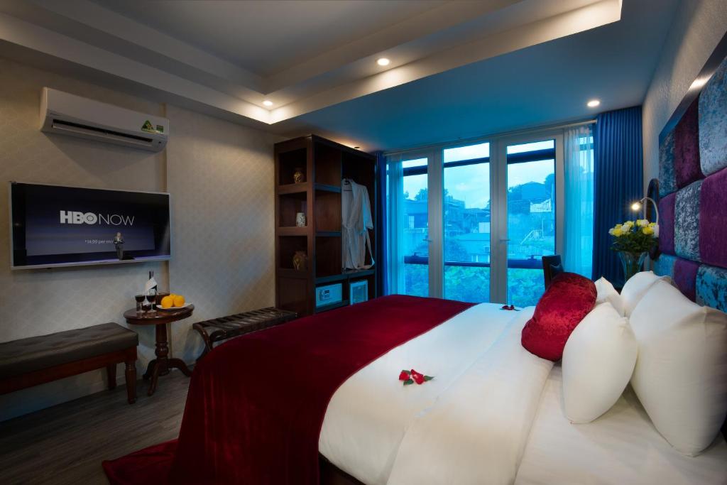 a bedroom with a large bed with red and white pillows at Lavender Boutique House in Hanoi