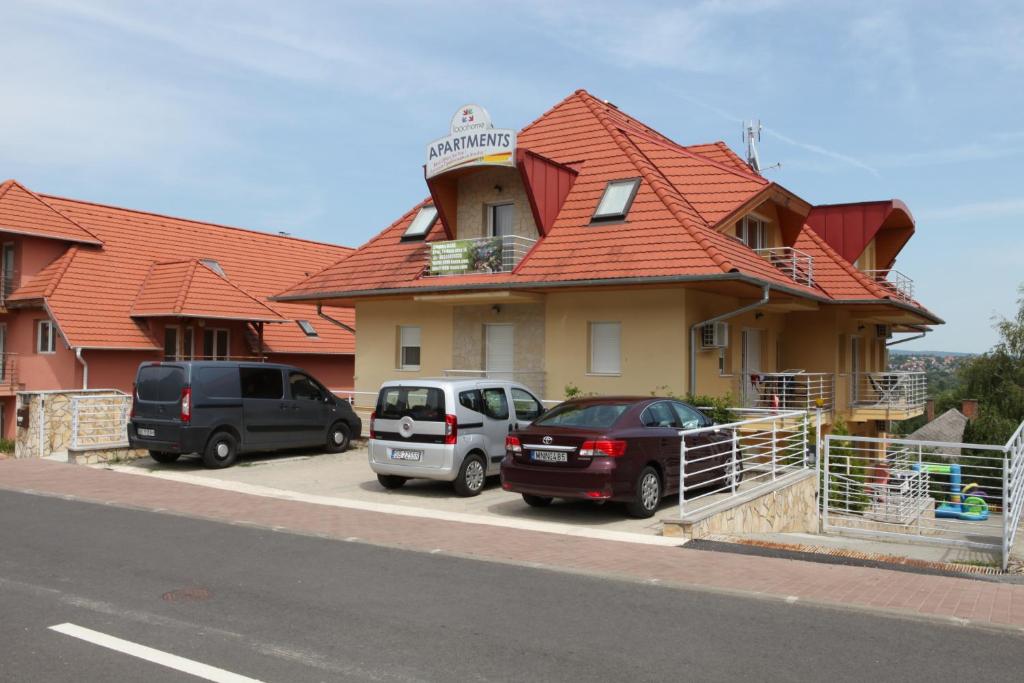 two cars parked in front of a house with an orange roof at Fortuna Lux apartments in Hévíz