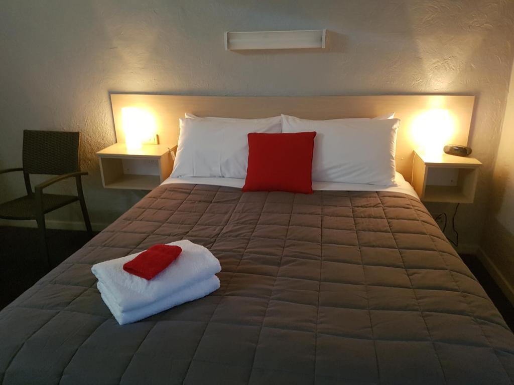 a large bed with two red pillows on it at Belmore Motor Inn in Yarrawonga