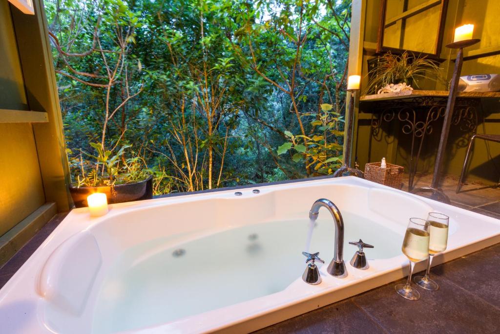 a bath tub in a bathroom with a large window at Wairua Lodge - Rainforest River Retreat in Whitianga