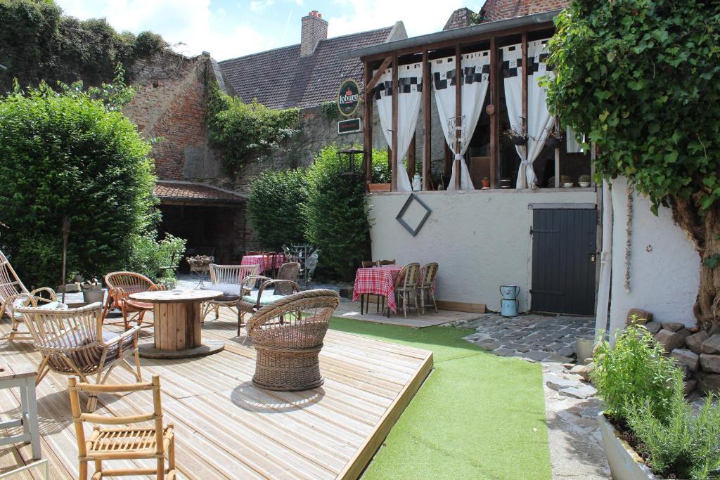 een patio met een tafel en stoelen op een houten terras bij Hypnos Hotel in Hesdin