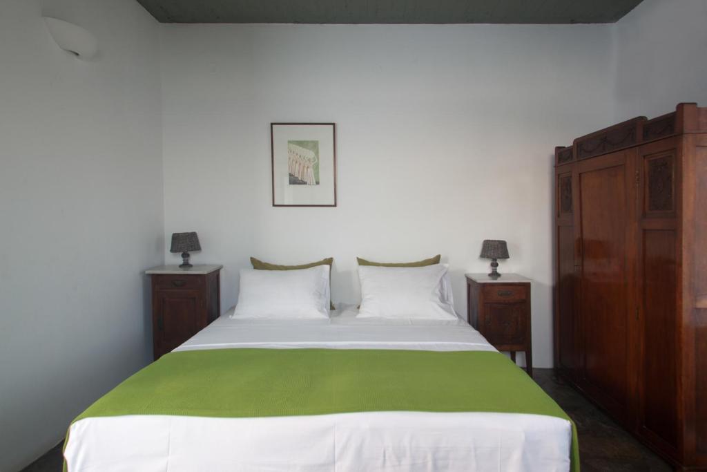 a bedroom with a white bed with a green blanket at Oliaros seaside complex in Agios Georgios