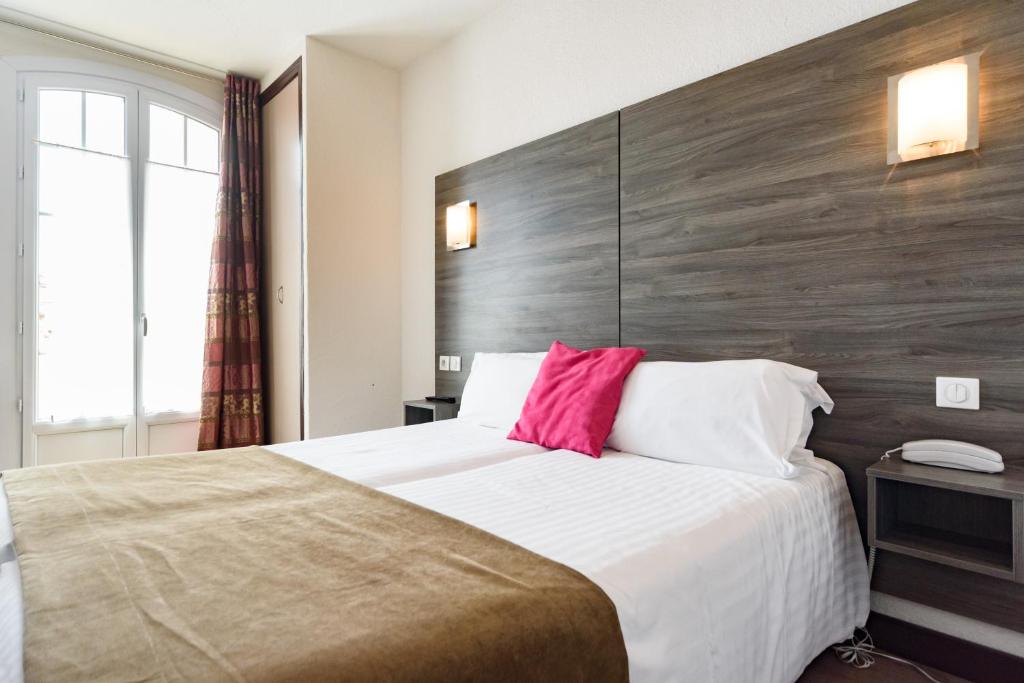 a bedroom with a large bed with a wooden headboard at Hotel Le 21 in Saint-Raphaël