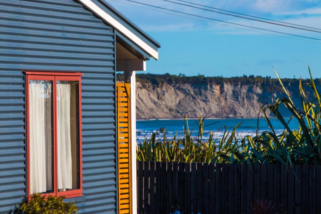 una casa con una ventana roja y una valla en BeachView Motel, en Greymouth