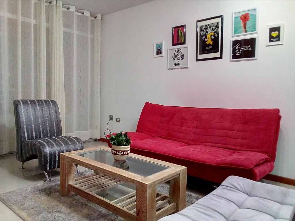 a living room with a red couch and a table at Hepico Departamentos Piura in Piura