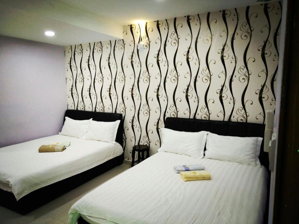 dos camas sentadas una al lado de la otra en una habitación en Leaf Guest House, en Kuantan