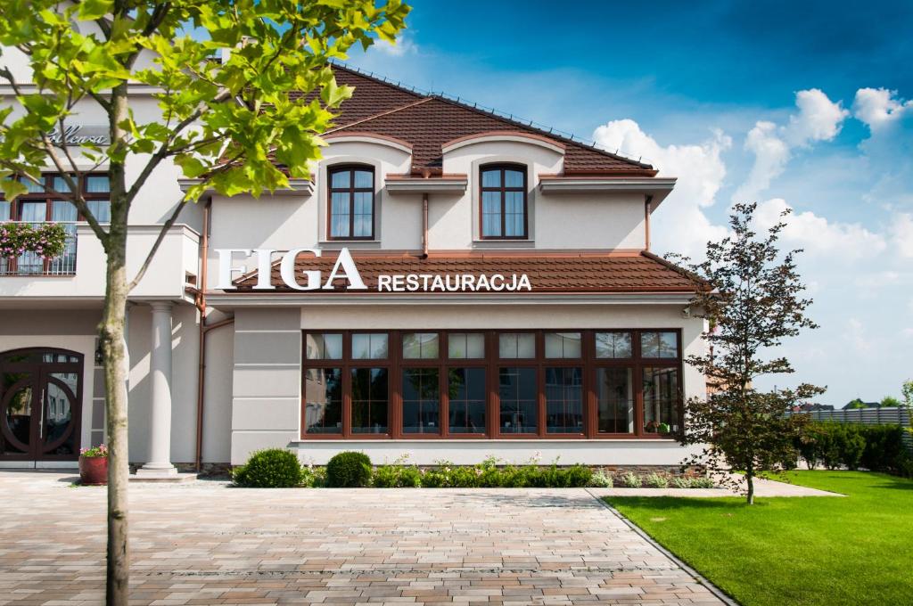 a large white building with a sign on it at Hotel Figa in Plewiska