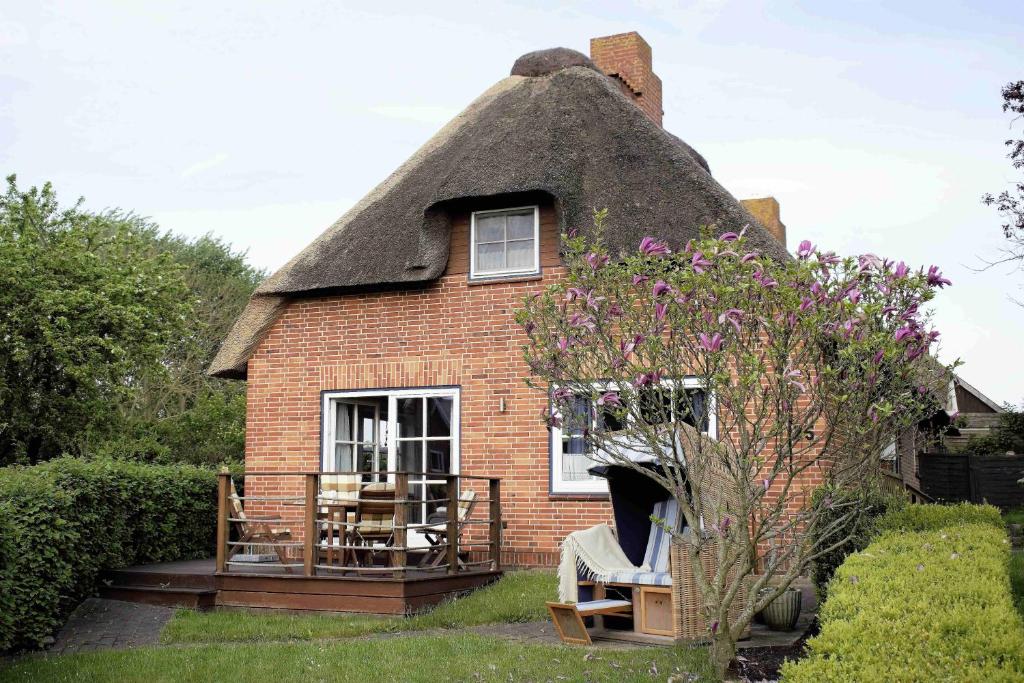 a thatch roofed house with chairs and a porch at Niels Hus in Dagebüll