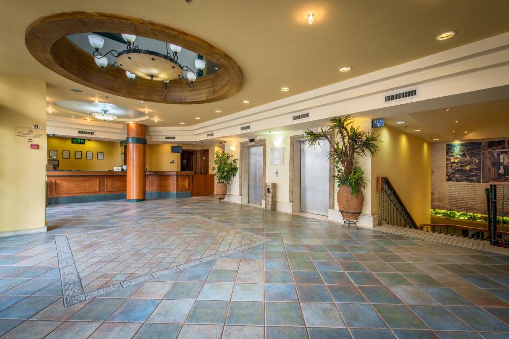 een lobby met een grote kamer met een potplant bij Mary’s Well Nazareth By Dan Hotels in Nazareth
