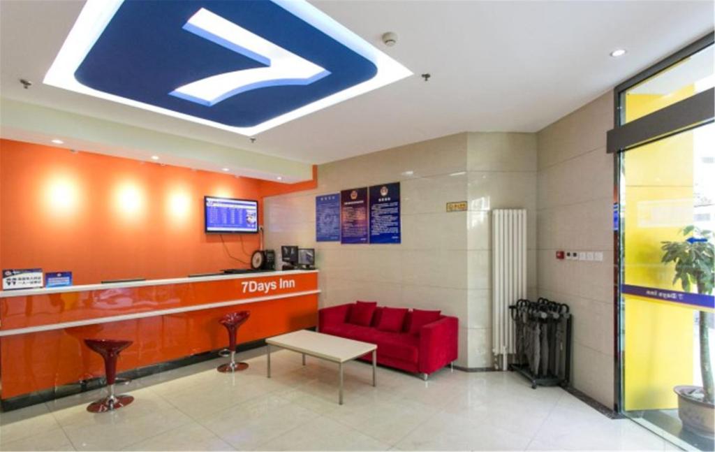 7Days Inn Beijing Yongdingmenwai Station في بكين: لوبي الفندق مع اريكه حمراء وعلامة على السقف