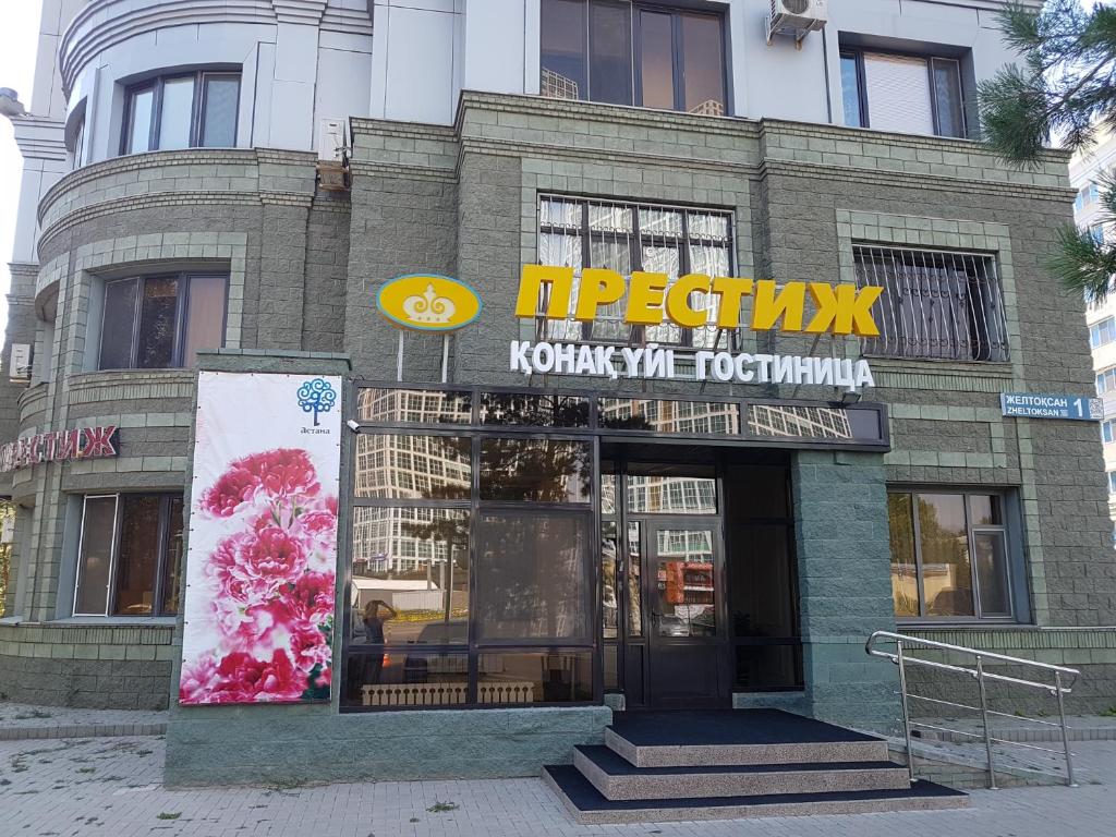 uma loja com uma placa na frente de um edifício em Prestige em Astana