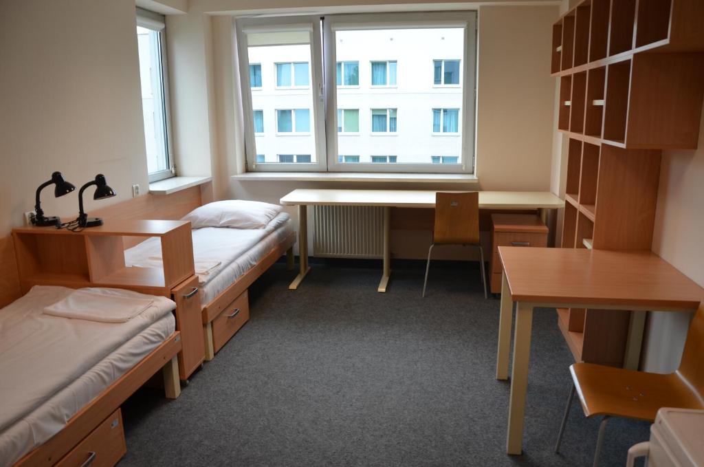 Zimmer mit Betten, einem Schreibtisch und einem Fenster in der Unterkunft DS Za Kolumnami in Krakau