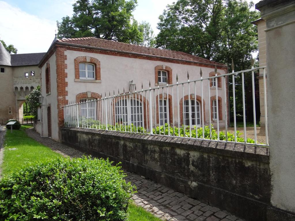 una casa vieja con una valla delante de ella en Château Mesny Gite Au Fil des Pages en Vic-sur-Seille