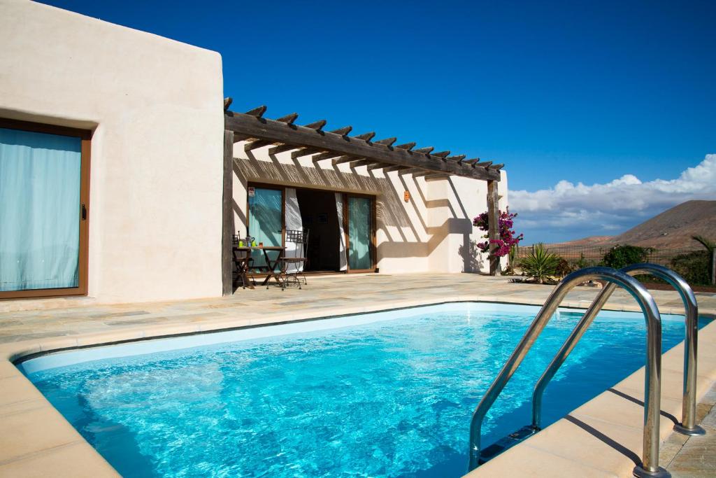 a villa with a swimming pool in front of a house at Villa Upupa in La Oliva