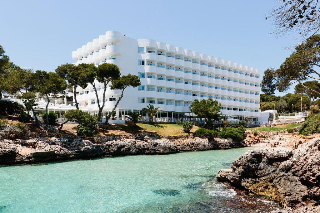 un bâtiment à côté d'une rivière en face d'un bâtiment dans l'établissement AluaSoul Mallorca Resort - Adults only, à Cala d´Or