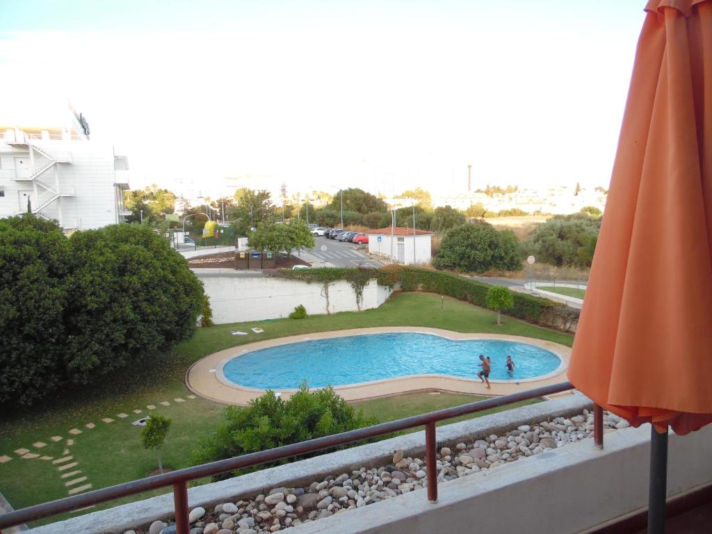 a balcony with an umbrella and a swimming pool at apartamento em albufeira in Albufeira