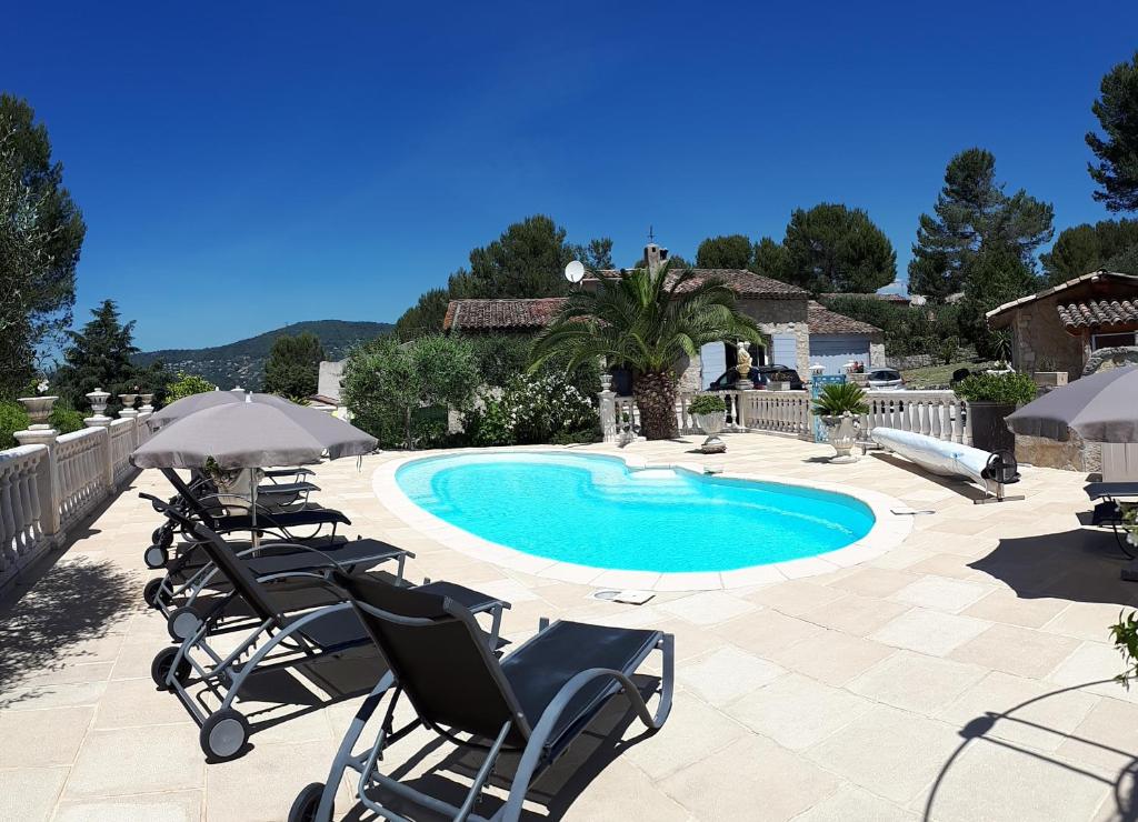 a pool with chairs and umbrellas in front at GITE LES PINS piscine chauffée jardin privatif climatisation Wifi parking in Peymeinade