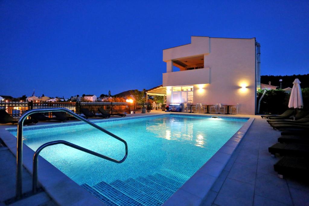 a swimming pool in front of a building at night at Vile Dalmacija in Preko