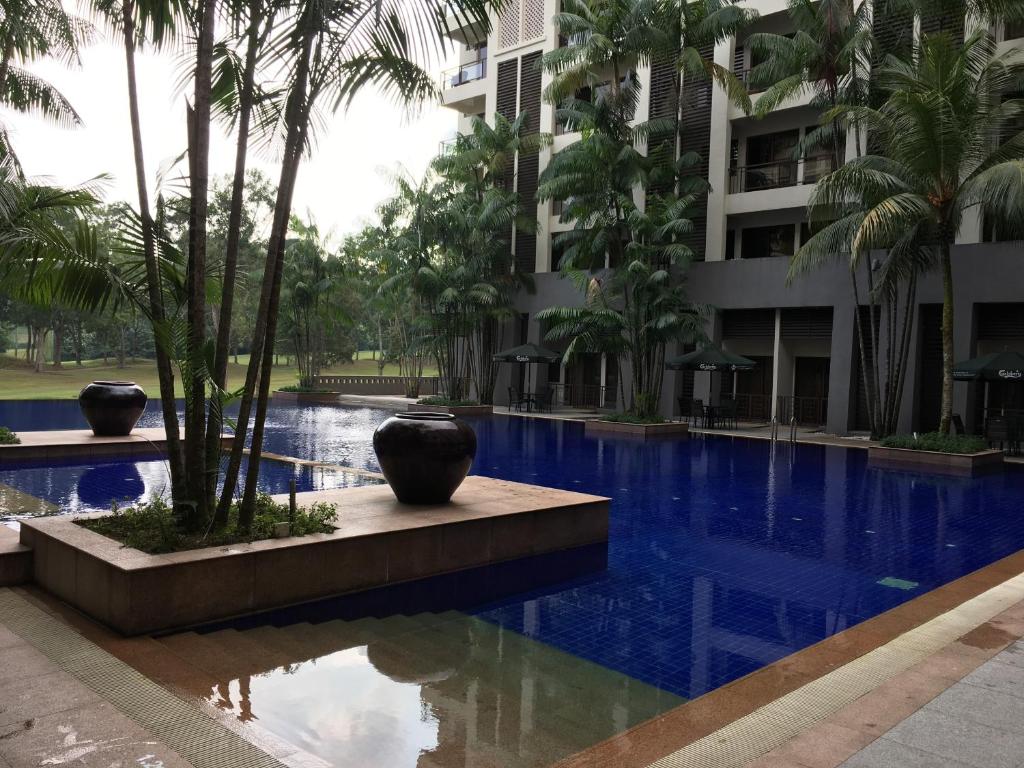a swimming pool in front of a building with palm trees at Ian's Vacation Rental in Skudai