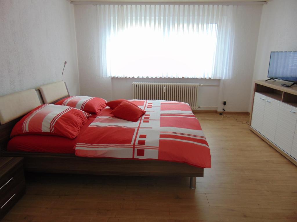 Un dormitorio con una cama con almohadas rojas y una ventana en Gästehaus Brandenburger, en Speyer