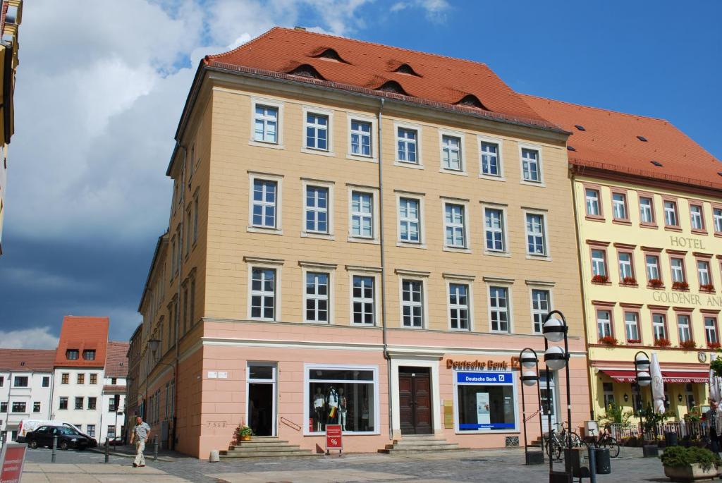 ein großes Gebäude mit rotem Dach auf einer Straße in der Unterkunft Ferienwohnungen in Torgau am Markt in Torgau