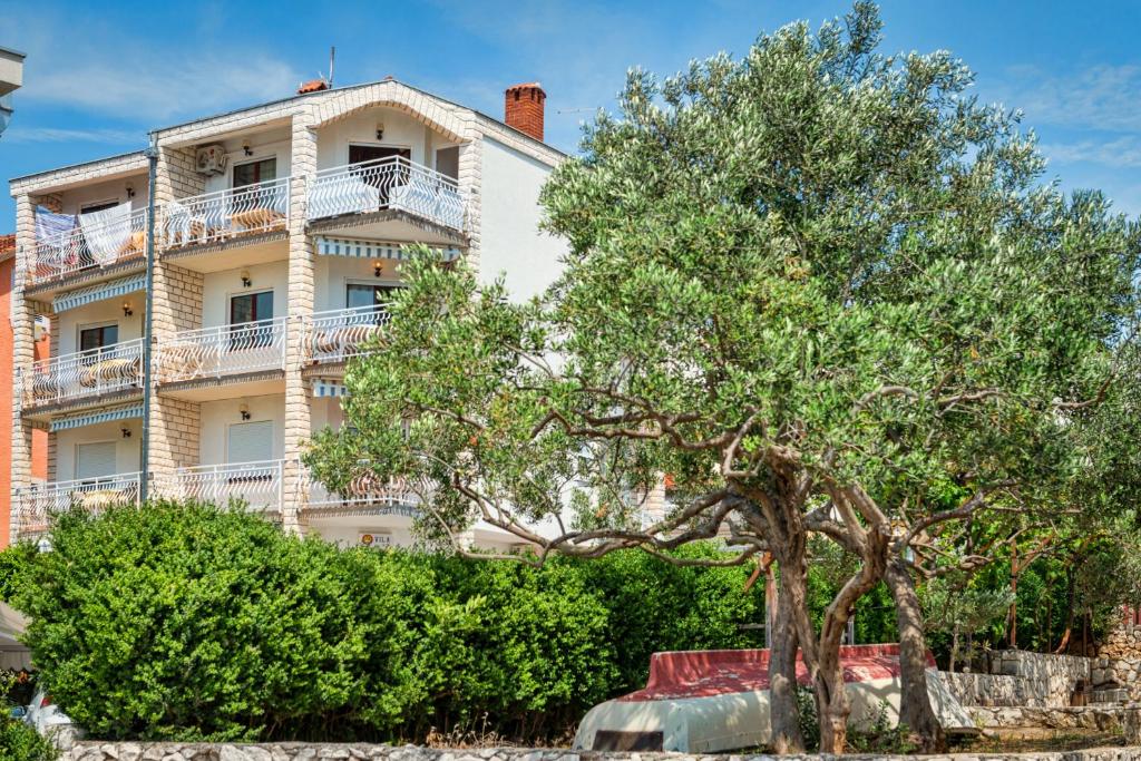 un edificio blanco con un árbol delante en Villa Daniela, en Trogir