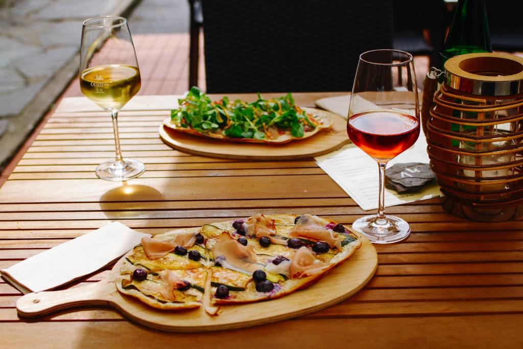 una mesa de madera con dos platos de pizza y copas de vino en Ferien Weingut Schneider, en Ellenz-Poltersdorf