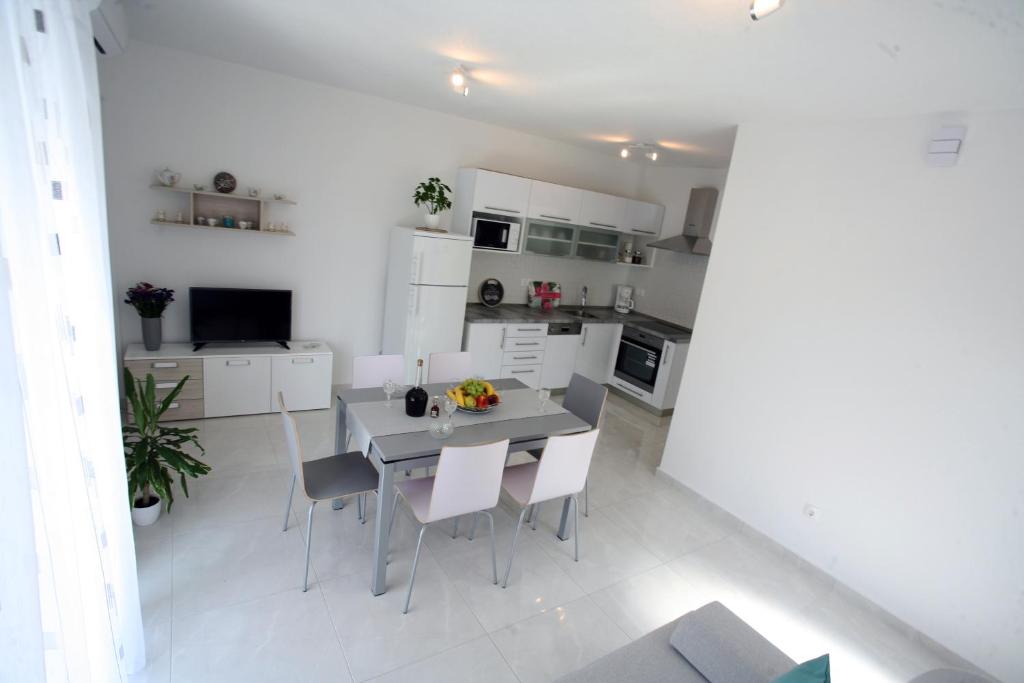 eine weiße Küche mit einem Esstisch und Stühlen in der Unterkunft Apartman Fantasy in Trogir