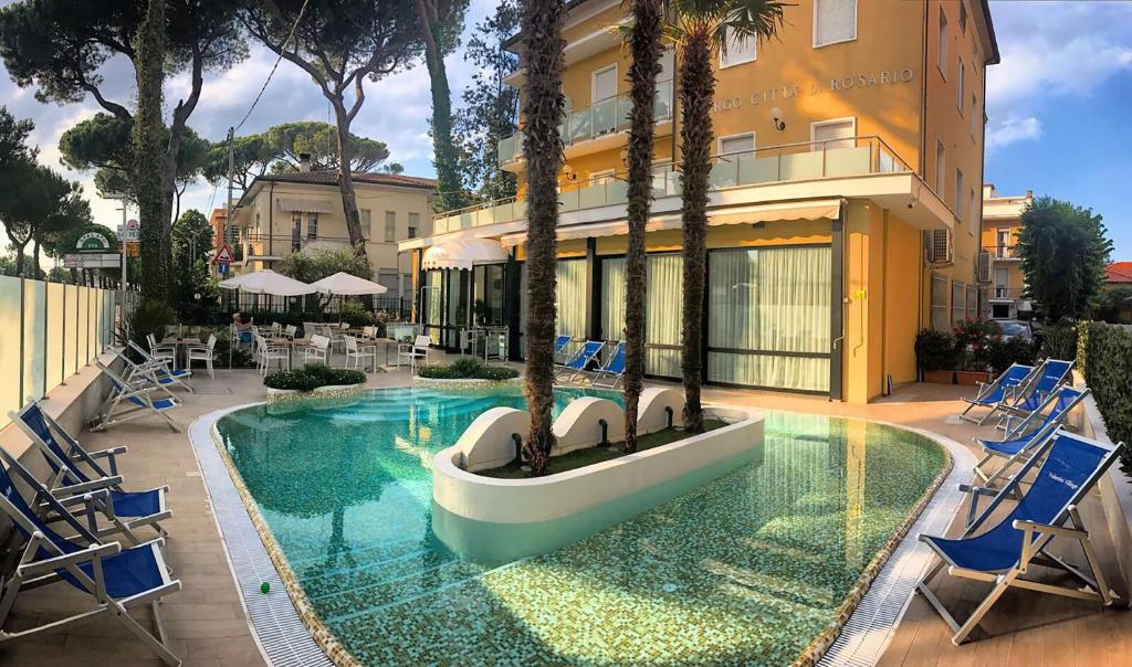 una piscina con sillas azules y un edificio en Hotel Maré - Valentini Family Village, en Bellaria-Igea Marina