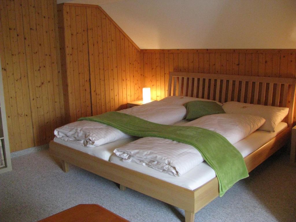 1 dormitorio con 1 cama con pared de madera en Zimmer & z'Morgä Schönenboden, en Wildhaus