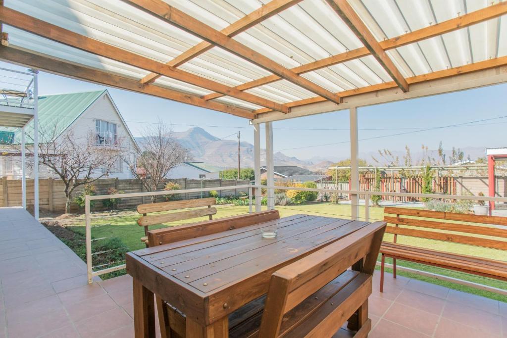 a patio with benches and a wooden table at Guest House Mooigezicht in Clarens